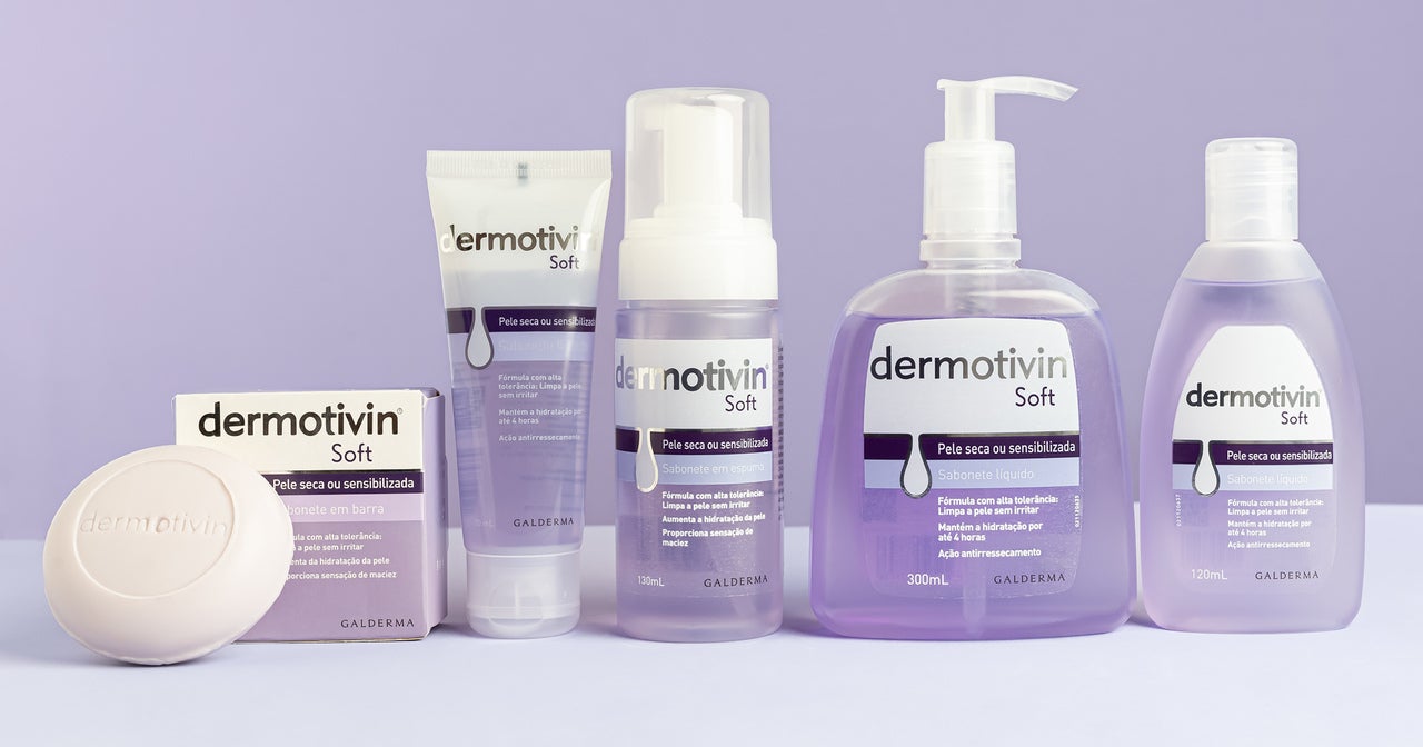 A imagem apresenta a linha de produtos Dermotivin Soft, desenvolvida para peles secas ou sensibilizadas. Os produtos estão organizados lado a lado sobre uma superfície plana com fundo lilás, criando um visual clean e delicado que transmite cuidado e suavidade.