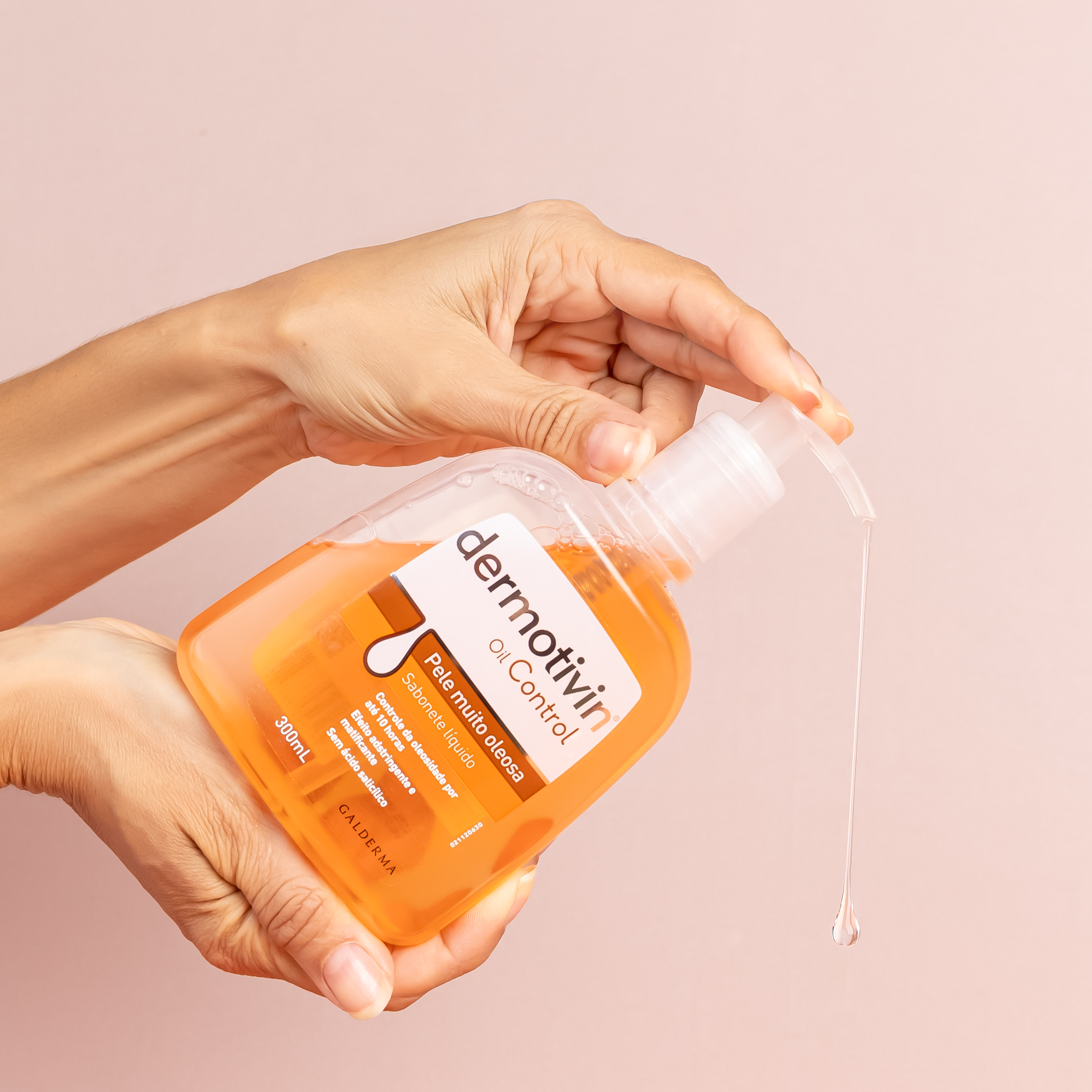 Mãos segurando Dermotivin Oil Control, sabonete facial líquido para pele oleosa, com produto escorrendo