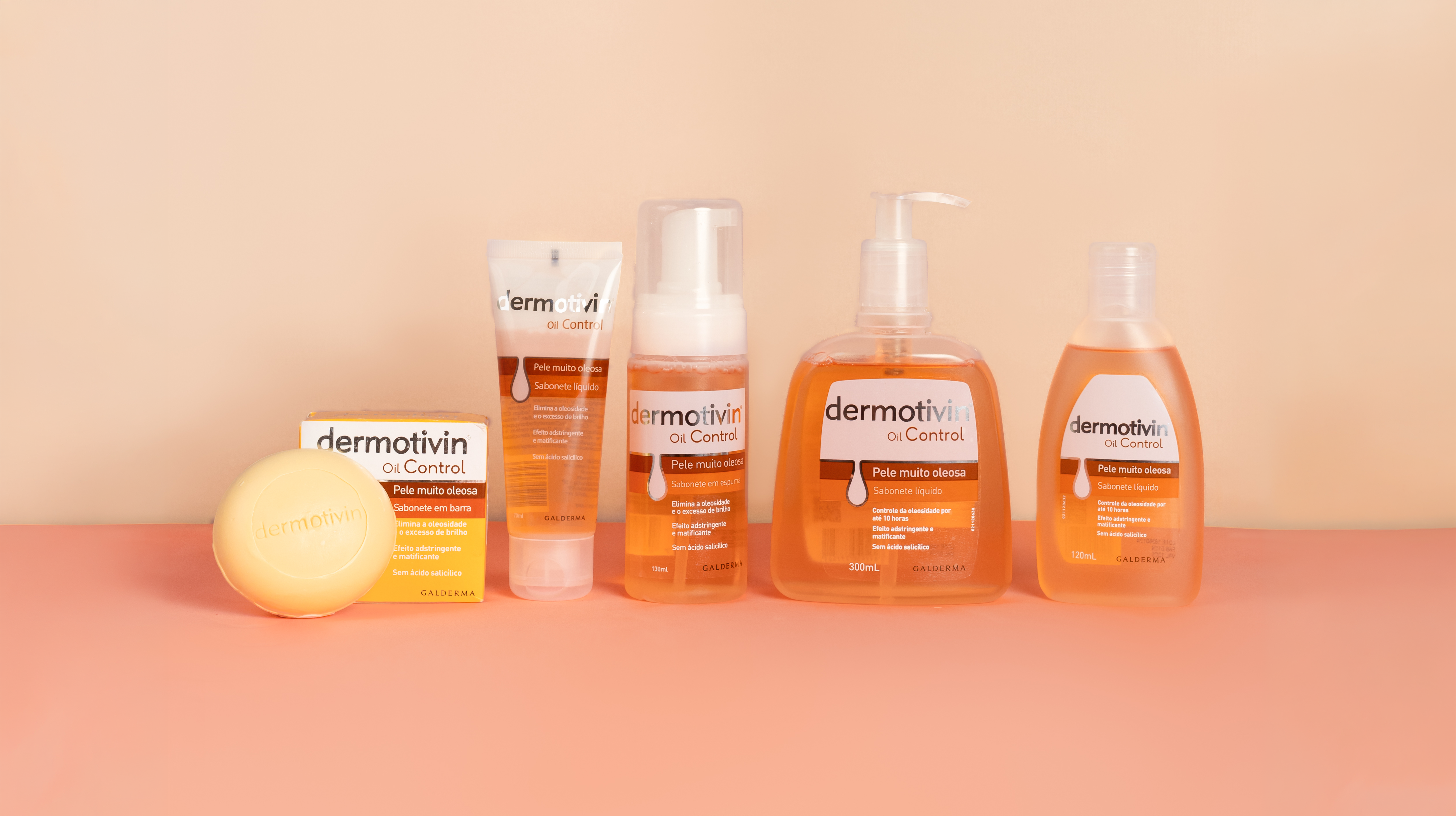 Linha Dermotivin Oil Control com sabonete em barra, sabonete líquido e sabonete em espuma sobre fundo laranja, ilustrando artigo sobre pele oleosa no inverno.