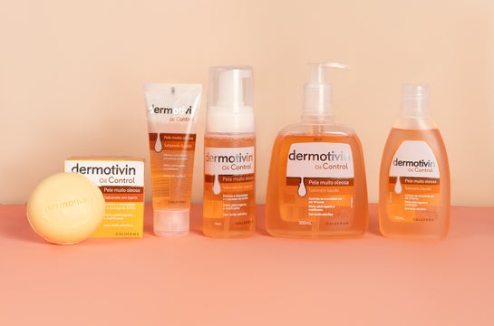 Linha Dermotivin Oil Control com sabonete em barra, sabonete líquido e sabonete em espuma sobre fundo laranja, ilustrando artigo sobre pele oleosa no inverno. 